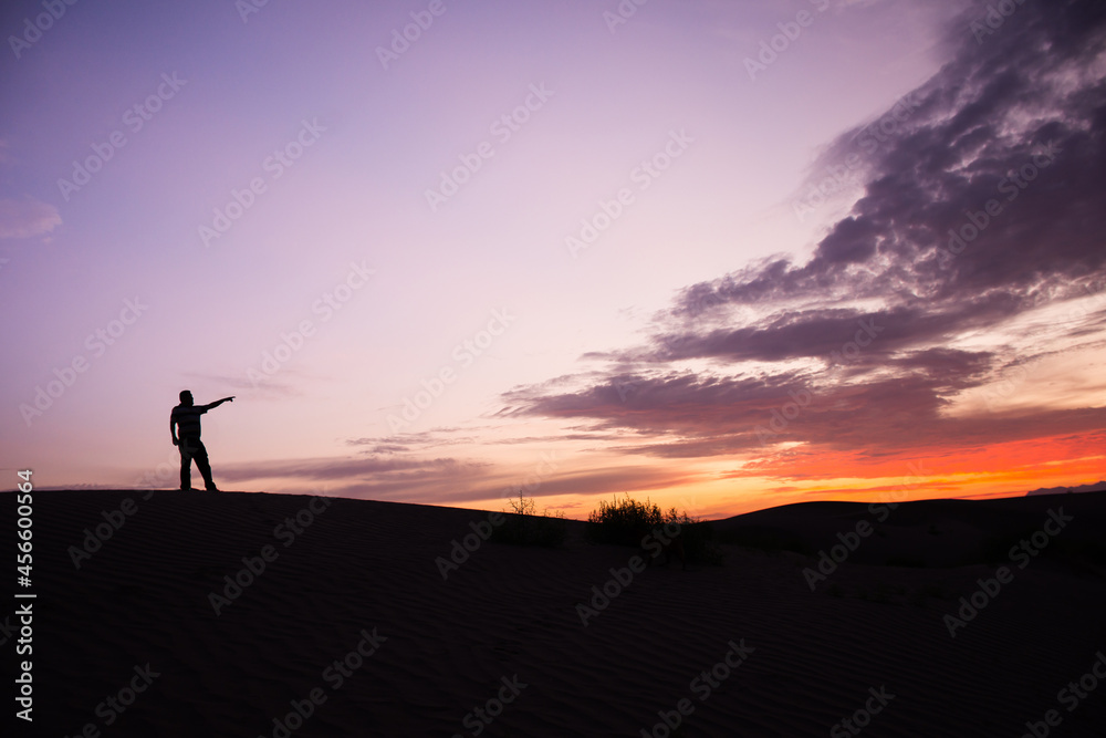 Silhouette of an unrecognizable man pointed the finger at sunset in the desert