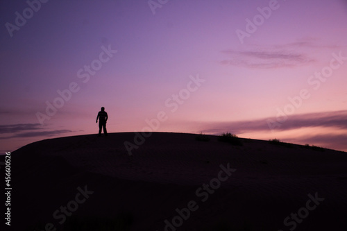 Silhouette of a man standing on a dune at sunrise