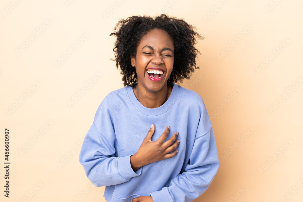 Fototapeta premium Young African American woman isolated on beige background smiling a lot