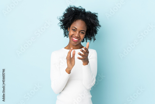 Young African American woman isolated on blue background applauding after presentation in a conference photo