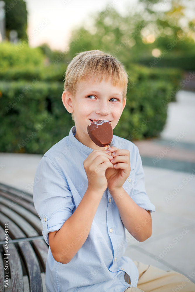 blonde boy in blue shirt eating popsicle ice cream blonde boy in blue shirt eating popsicle ice cream