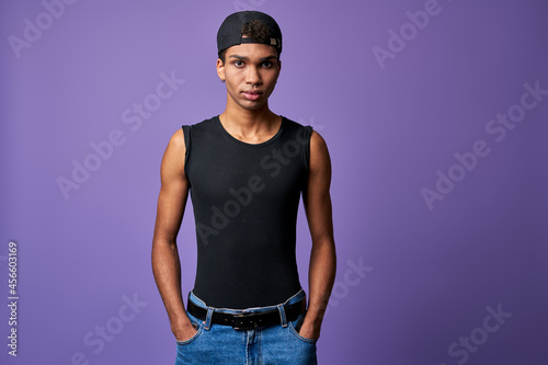 Portrait young transgender brunette man in black t-shirt, cap, blue jeans. Hispanic trans gender male