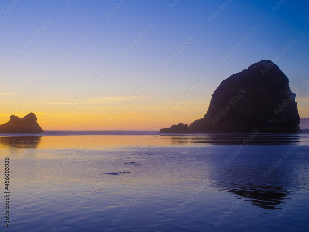 Large and small rocks in the ocean. Sunset. Beautiful sky in the rays of the setting sun. The beauty of nature, calm scenes. Travel, romance, advertising, postcard. Empty space to insert.