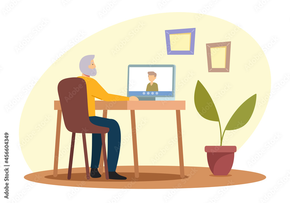 Elderly People Hobby Concept. Senior Grey Haired Man Sitting at Desk with Laptop Chatting with Relatives via Internet