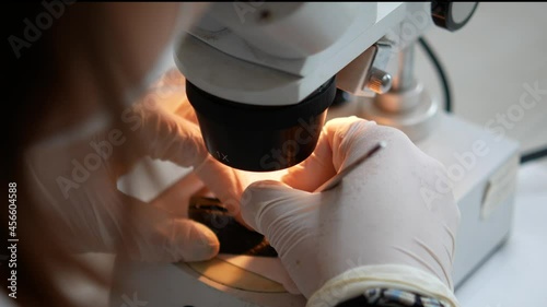 Conservation of archaeological finds in the laboratory. An archaeologist in protective gloves under a microscope cleans a metal object from Roman times. Processing of archaeological objects