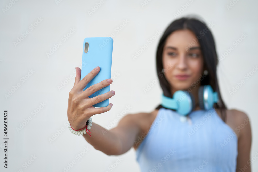 woman taking a selfie with the smartphone with headphones on her neck woman taking a selfie with the smartphone with headphones on her neck