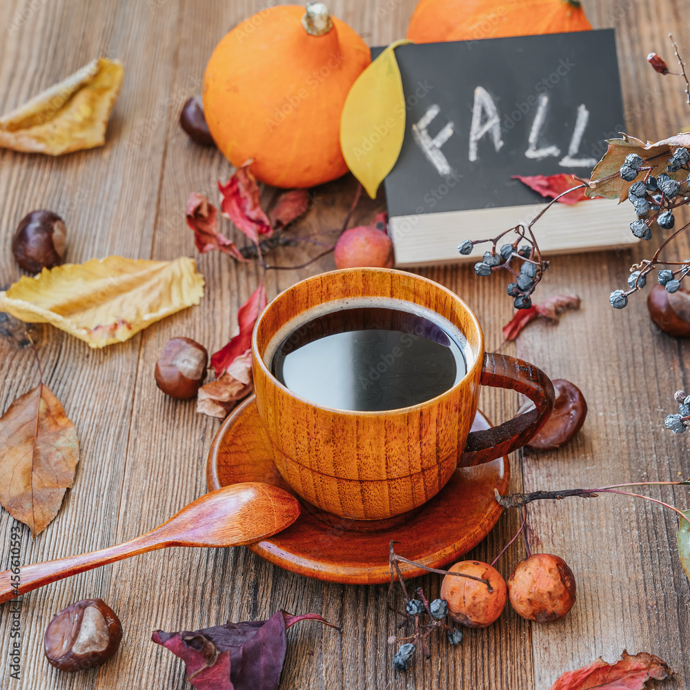 Cup of coffee, faded leaves, chestnuts, nuts, board inscription Fall. Concept of leaf fall, autumn