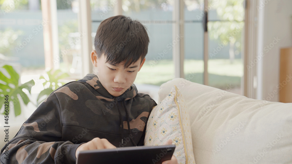 Mixed Asian preteen teen boy making video calling with digital tablet at home, using zoom online virtual class , social distancing, homeschooling, remote learning, new normal concept Mixed Asian preteen teen boy making video calling with digital tablet at home, using zoom online virtual class , social distancing, homeschooling, remote learning, new normal concept