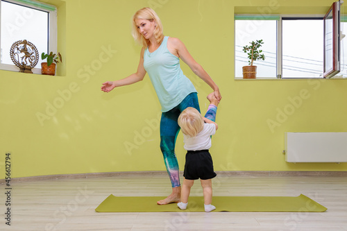 Mom and baby are doing yoga in the hall.