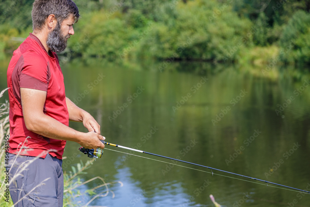 A man with a beard is fishing on the river.