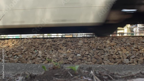 Train wheels passing by on gravel railway in front of houses in Japan photo