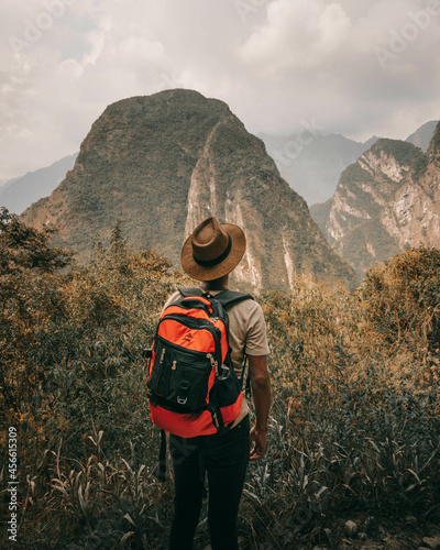 Explorator hikking with backpack in the jungle with a hat and montain views photo