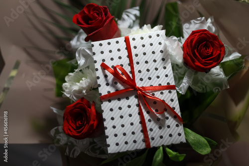 3 red roses  bouquet with gift envelope, red ribbons, white paper for certificates, invitation card inside. Craft concept. Red on the red background.   Weddig, ceremony concept, holidays, surprises. photo