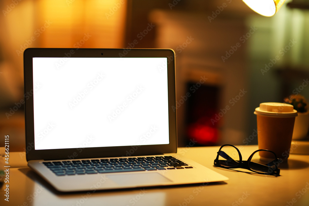 Fototapeta premium Modern laptop, glasses and coffee on table in evening