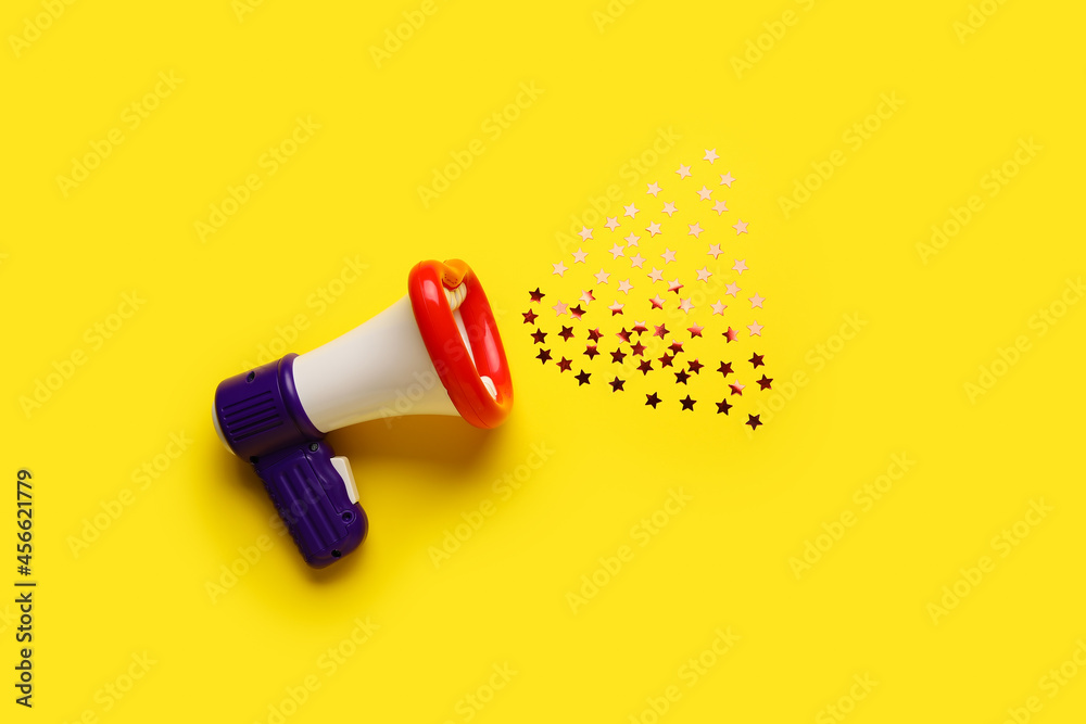 Toy megaphone with confetti on color background Stock Photo | Adobe Stock