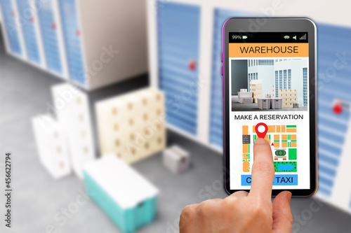 storage company website. Rental Storage Units using smartphone. Make reseration warehouse. Man's hand using phone. Sellphone with site for rental storage. Blurred warehouse corridors in background.
