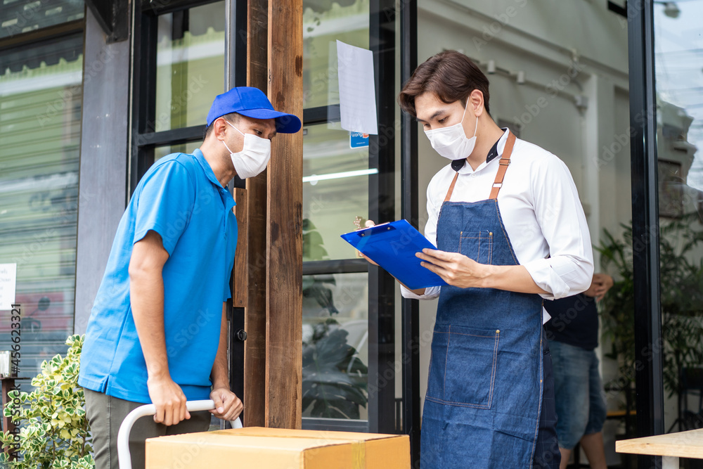 Asian Postman deliver food ingredient box to restaurant waiter in cafe Asian Postman deliver food ingredient box to restaurant waiter in cafe