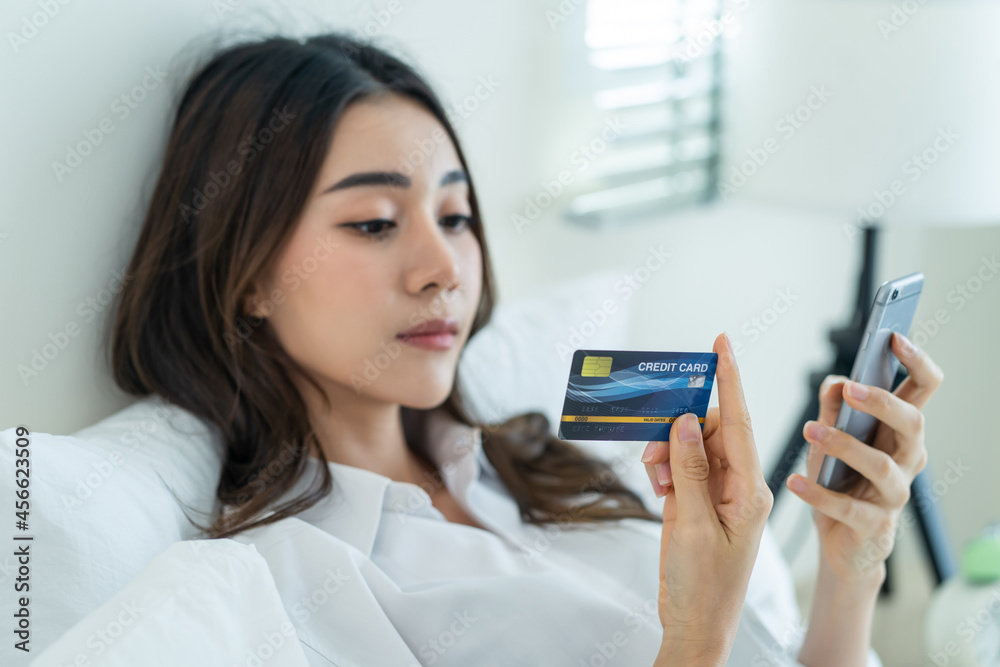 Asian attractive woman enjoy shopping online on bed at home in morning Asian attractive woman enjoy shopping online on bed at home in morning