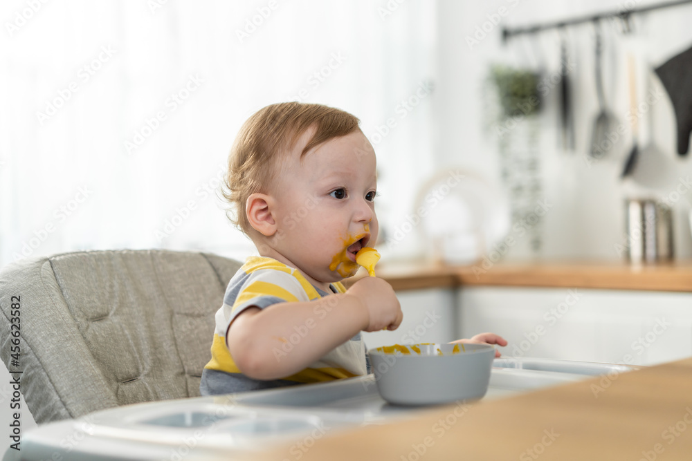 Caucasian young baby toddler eating healthy foods in kitchen at home. Caucasian young baby toddler eating healthy foods in kitchen at home.