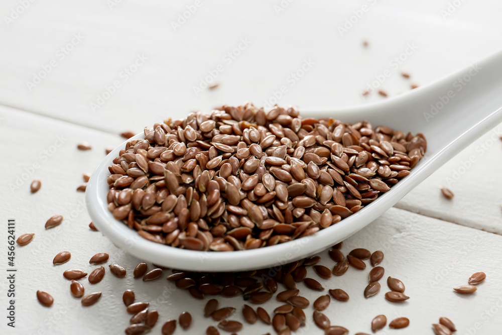Spoon with flax seeds on light wooden background, closeup Spoon with flax seeds on light wooden background, closeup