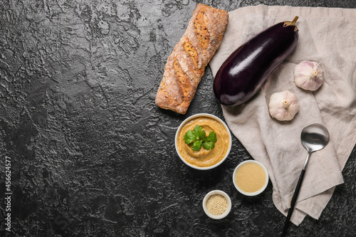 Bowl with tasty baba ghanoush and ingredients on dark background photo