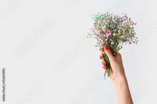 Woman with beautiful manicure holding bouquet of flowers on white background