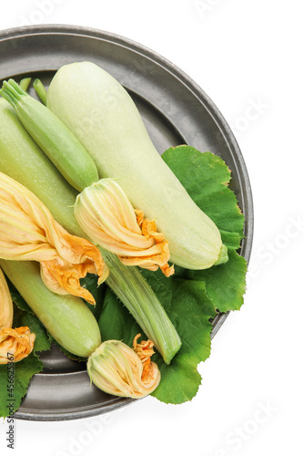 Tray with fresh zucchini and flowers on white background