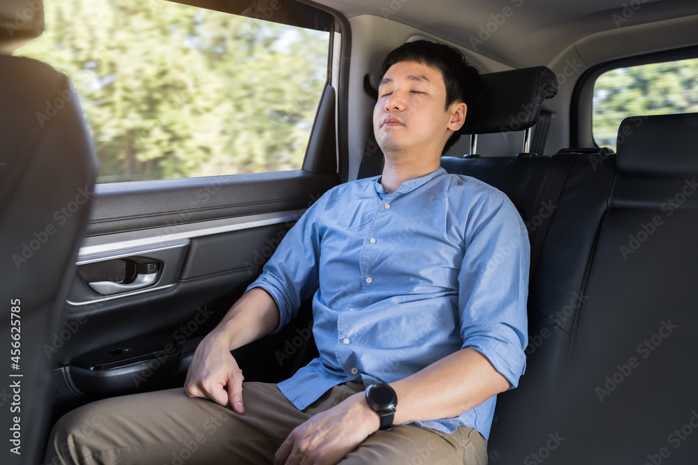 man sleeping while sitting in the back seat of car