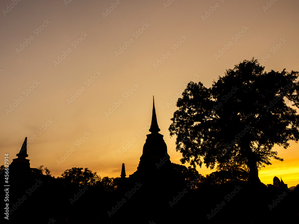 Amazing scenetic of silhouette of pagoda, temple and gold sunset sky in Sukhothai Historical Park, a UNESCO World Heritage Site in Thailand.