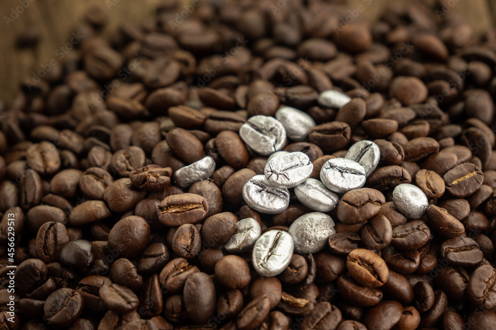 Naklejka premium Silver coffee beans on a pile of coffee beans. The concept of luxury is extraordinary