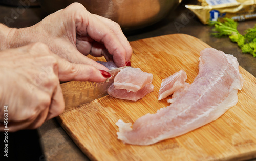 Chef cuts fish fillets on wooden board for cooking
