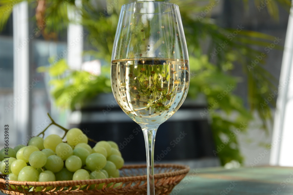 A glass of white wine with grapes on wooden table. White wine Riesling, from white grapes A glass of white wine with grapes on wooden table. White wine Riesling, from white grapes