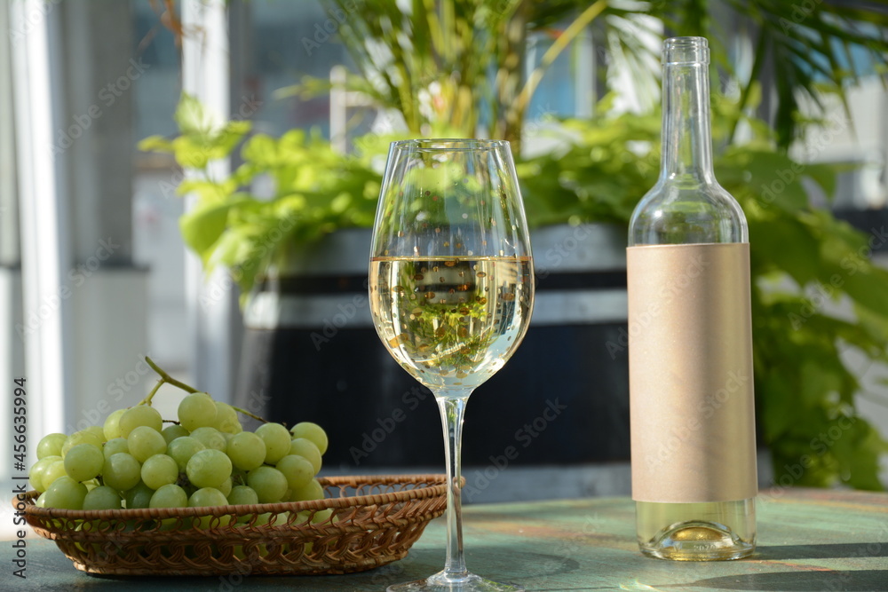 A glass of white wine with grapes on wooden table. White wine Riesling, from white grapes A glass of white wine with grapes on wooden table. White wine Riesling, from white grapes