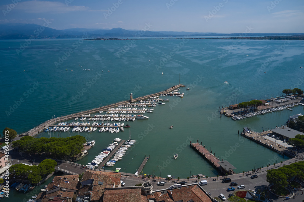 Aerial panorama of the town of Desenzano del Garda on Lake Garda in Italy. Italian resorts on Lake Garda. Top view of the coastline, boat parking on the lake. Aerial view of Desenzano del Garda.