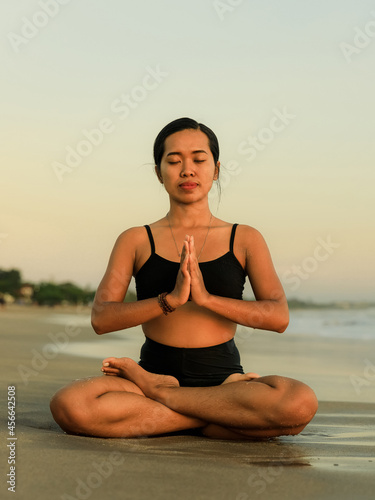 Yoga retreat. Asian woman practicing Lotus pose. Padmasana. Hands in namaste mudra. Closed eyes. Healthy lifestyle. Yoga on the beach. Copy space. Seminyak beach  Bali