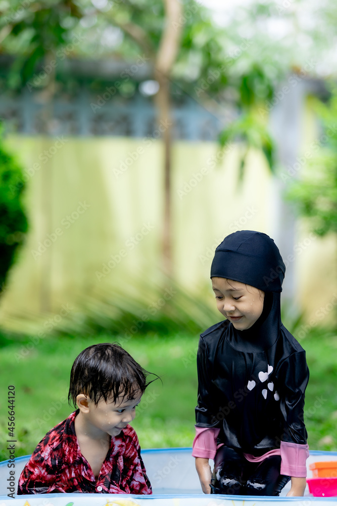 Asian boy and girl playing water in the garden Asian boy and girl playing water in the garden