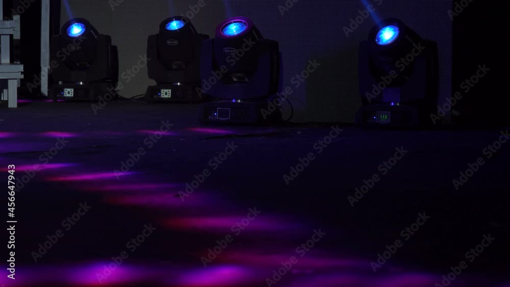 Four colored projectors on the stage lights farm. Bright shiny stage lights flashing movement entertainment spotlight projectors in the dark, blue soft light spotlight strike on black background.