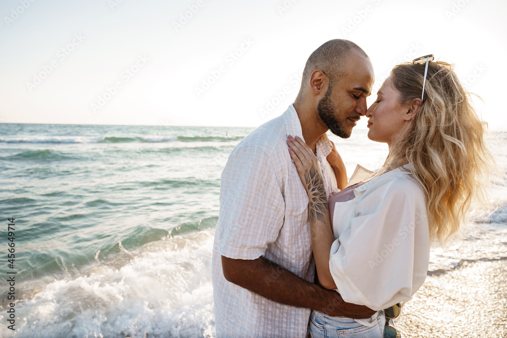 Beautiful young couple hugging on the beach by the water Beautiful young couple hugging on the beach by the water
