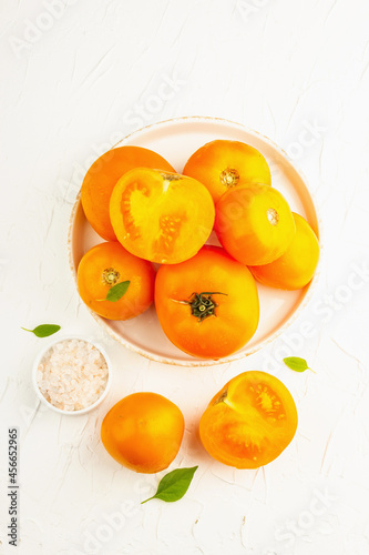 Ripe orange tomatoes with fresh basil. New harvest vegetables on a ceramic stand © FuzullHanum