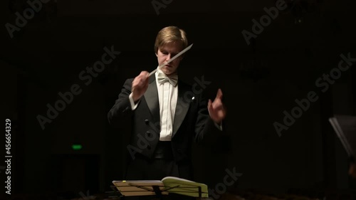 The camera zooms in on the leader of the symphony orchestra. Young conductor leads the orchestra
