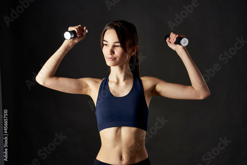 sports woman with dumbbells in hands workout fitness dark background