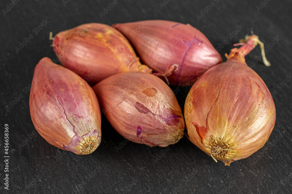 Fototapeta premium Group of five whole shallot on grey stone