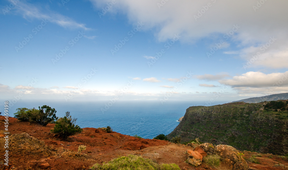 Wide angle shot of beautiful coastline on the Canary island of La Gomera in spring with seashore, mountains, vegetation, sky, clouds and sun; Spain in Europe