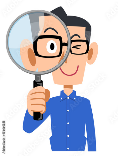 虫眼鏡を覗くメガネをかけて青いシャツを着た男性
