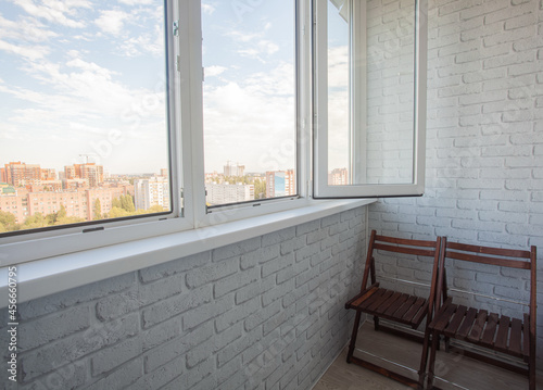 Cozy balcony with white brick walls and two wooden chairs