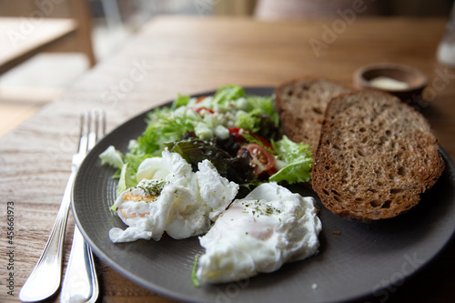 Fried Eggs on Wholegrain Toast and green salad for Breakfast. on wooden table