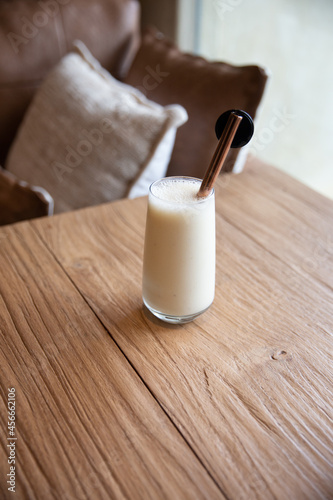 healthy breakfast. banana smoothie in glass and straw on a wooden background