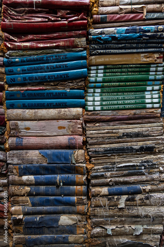 Venice, Italia - August 04 - 2021 Background wallpaper of ancient books piled on top of each other. Ancient bookshop in Venice with all books stacked one on top of the other, ruined by time.
