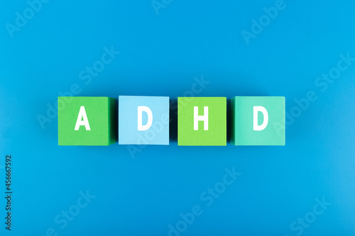 Minimal modern concept of Adhd awareness in blue color. Top view of multicolored blocks with written Adhd letters against blue background with light gradient