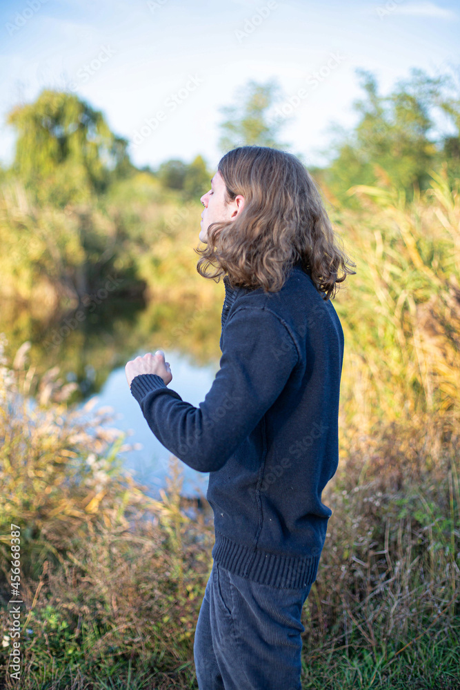 White european young man with blonde hair with lake behind White european young man with blonde hair with lake behind